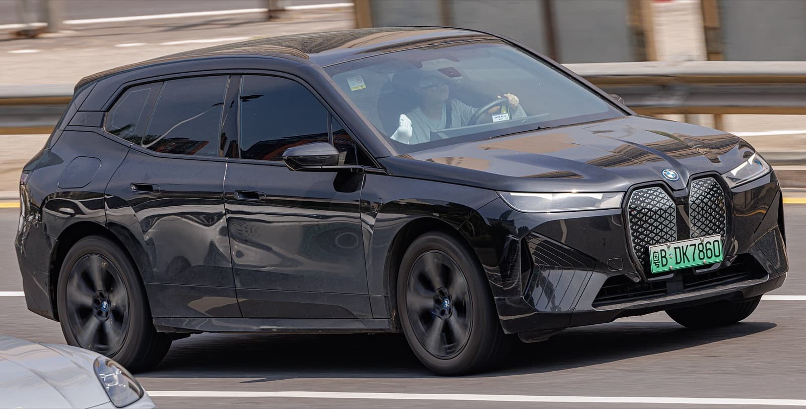A black BMW iX electric SUV driving on a road