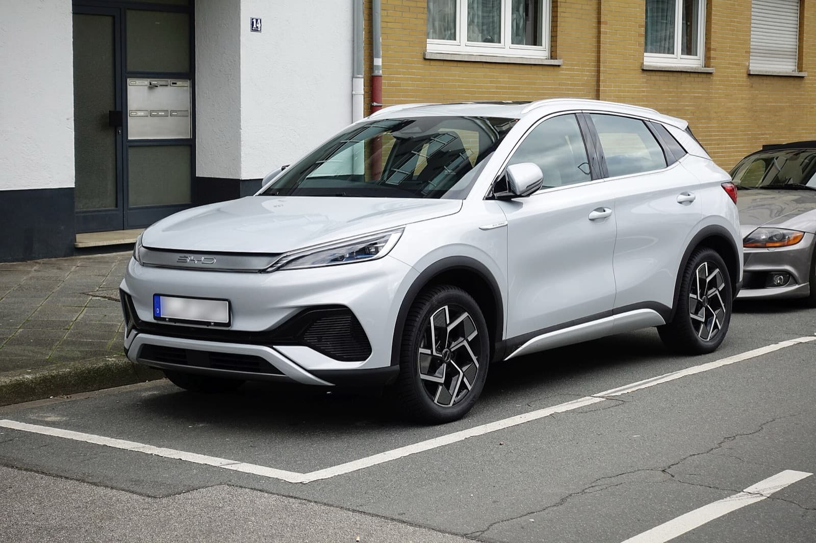 A silver BYD Atto 3 electric compact SUV parked on a city street, front three-quarter view