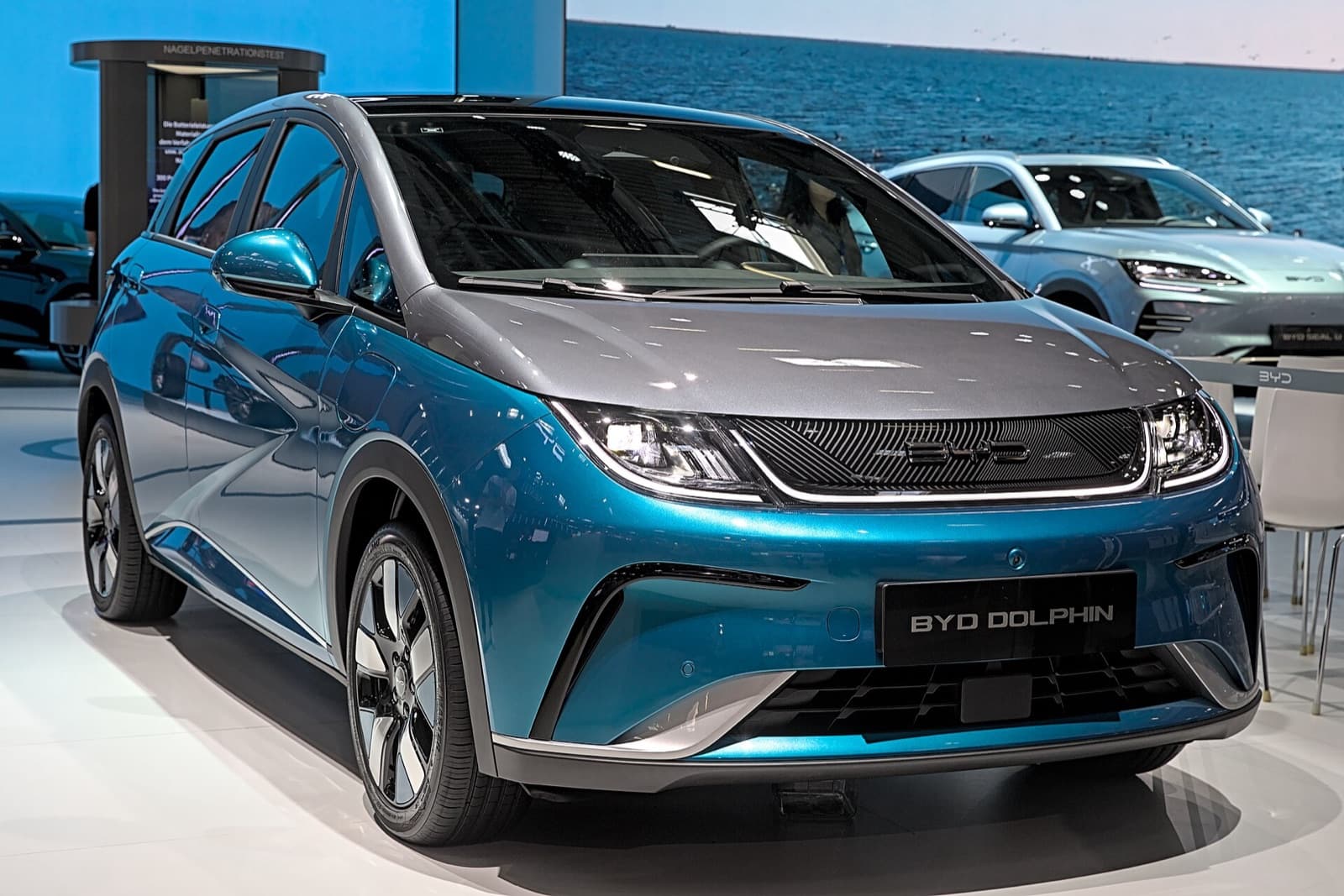 A teal blue BYD Dolphin electric hatchback at the IAA 2023 motor show, front three-quarter view