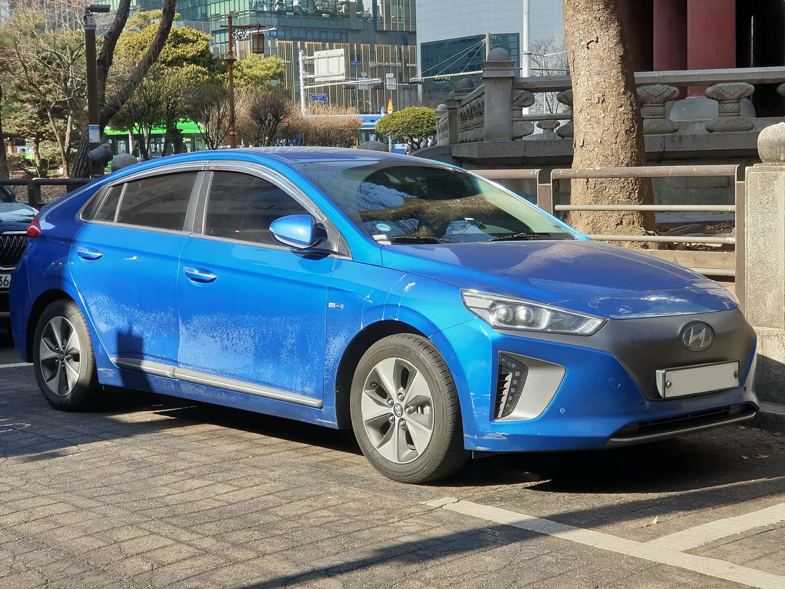 A blue first-generation Hyundai Ioniq Electric hatchback parked on a city street
