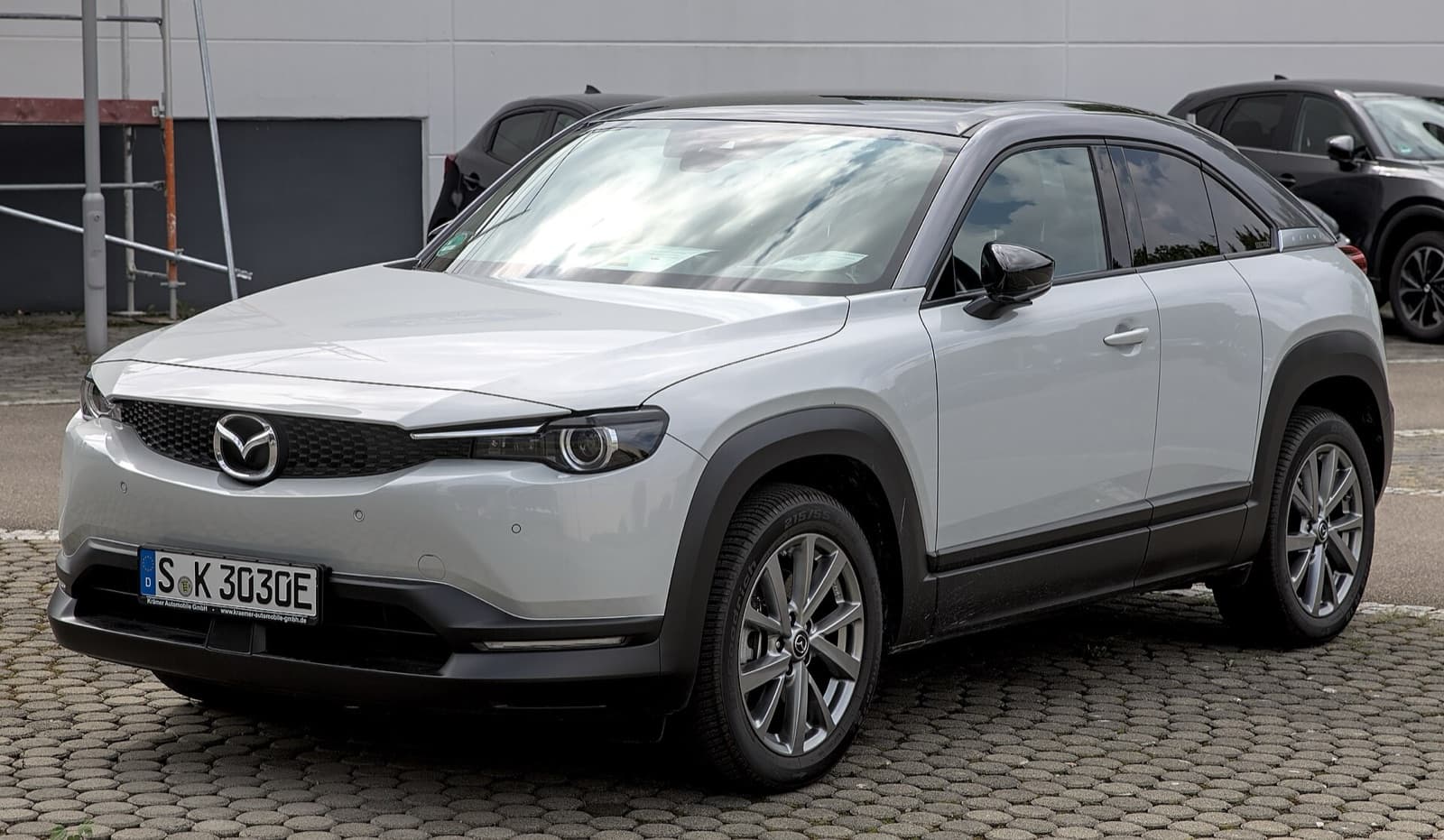 A white Mazda MX-30 electric SUV parked on a paved lot