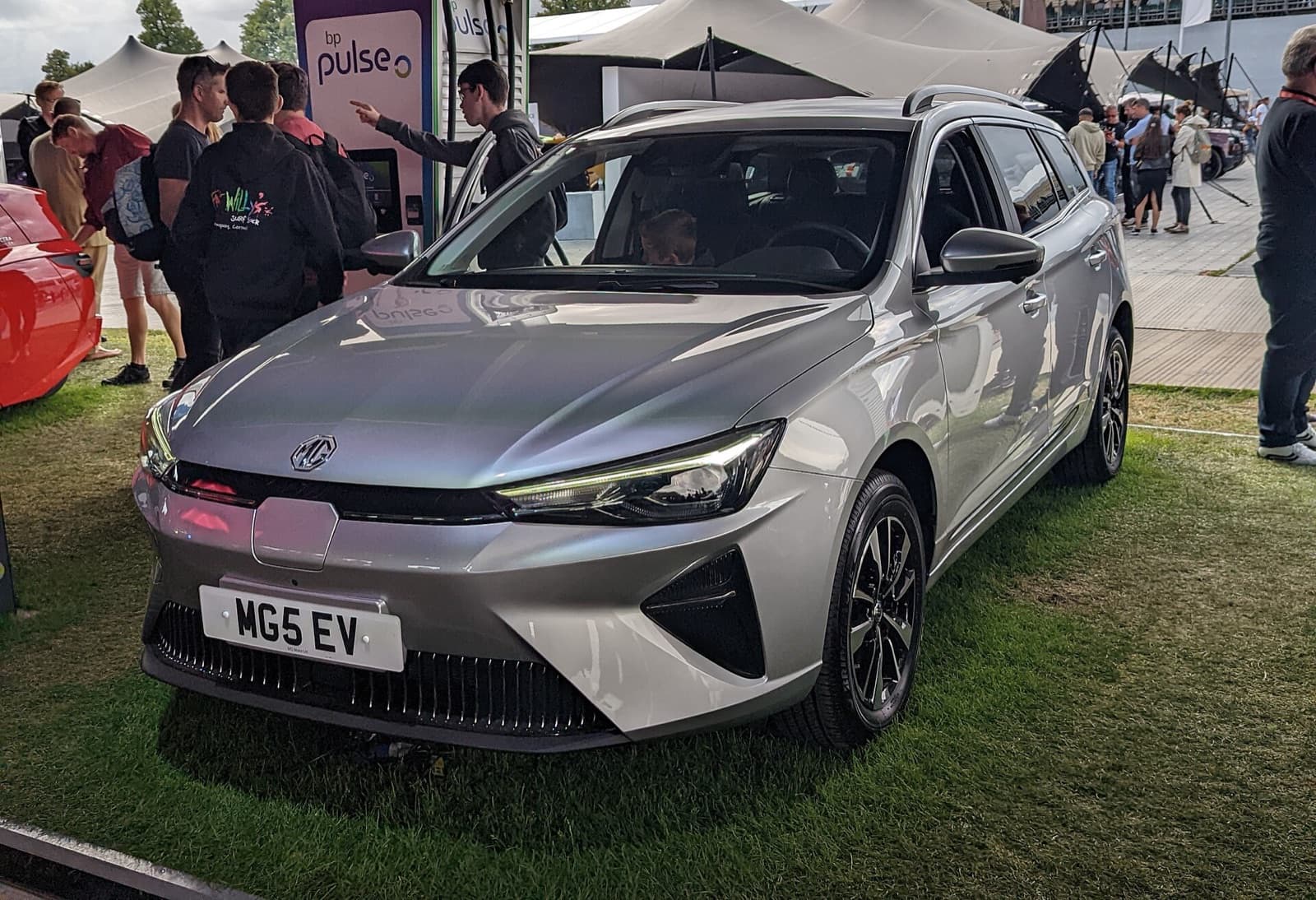 A silver MG 5 EV electric estate on display at an outdoor event, front three-quarter view