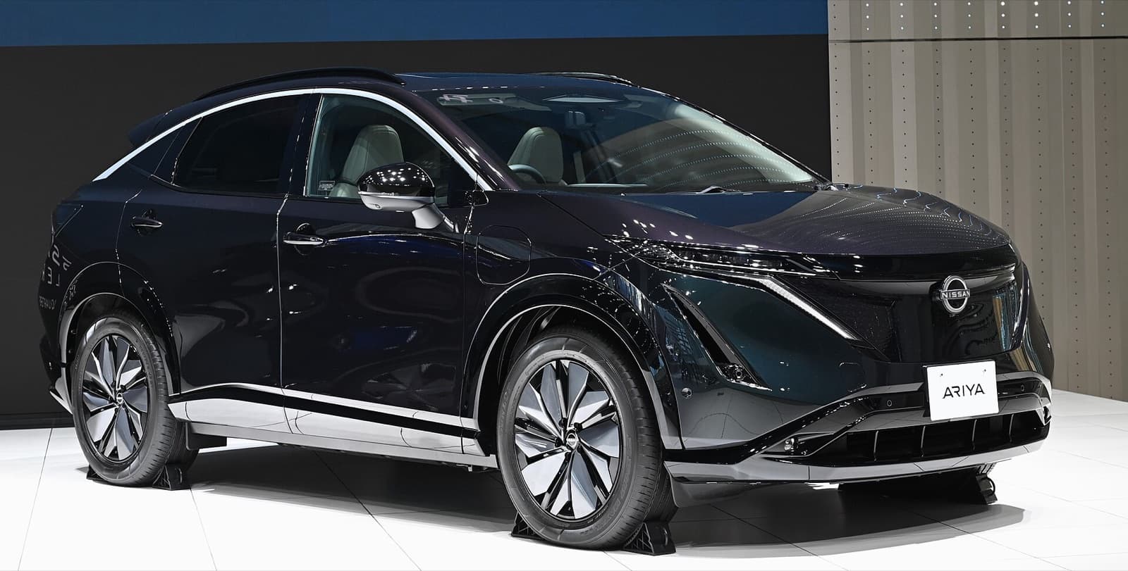 A dark Nissan Ariya electric crossover SUV on a motor show stand