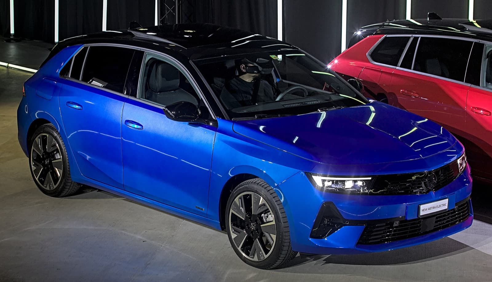 A blue Vauxhall Astra Electric hatchback on display at a motor show