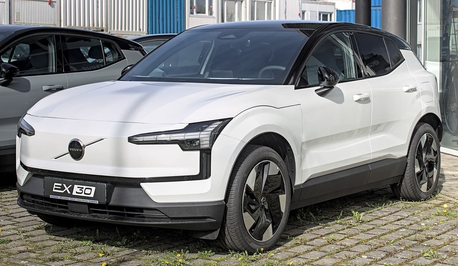 A white Volvo EX30 small electric SUV parked at a dealership
