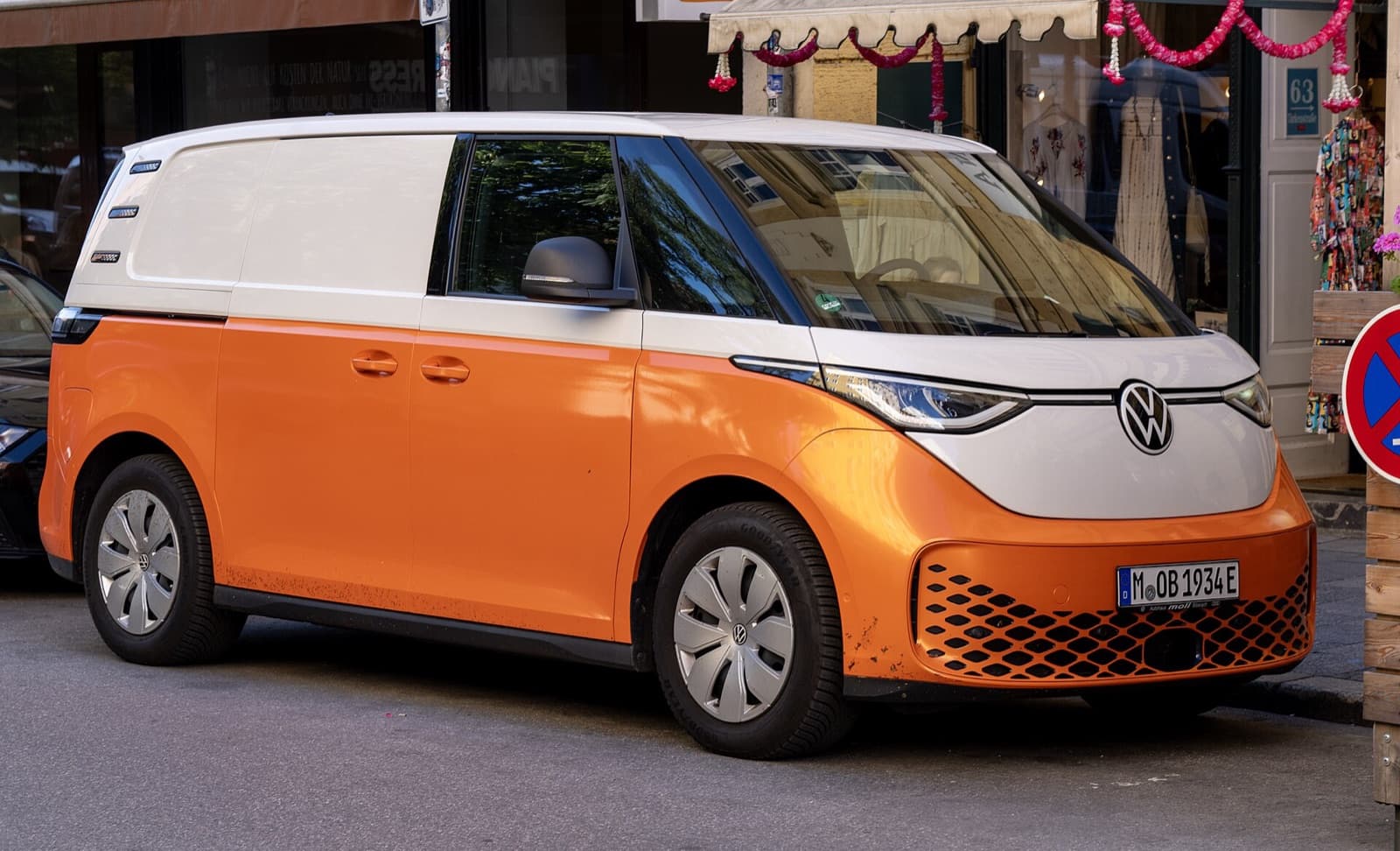 An orange-and-white two-tone Volkswagen ID. Buzz electric van parked on a Munich street