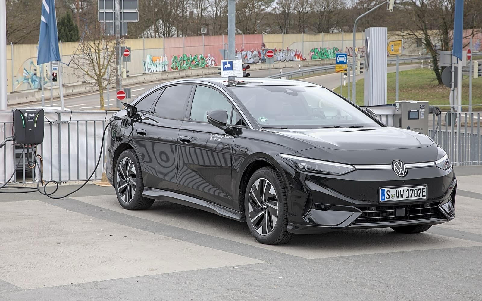 A black Volkswagen ID.7 electric fastback plugged into a charging station